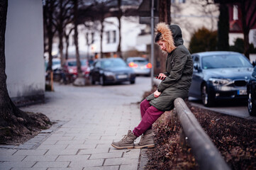 Urban Woman Texting on Street. Woman in winter attire using phone on city sidewalk - Powered by Adobe