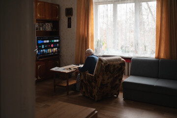 Senior Man Contemplating by Window, watching TV