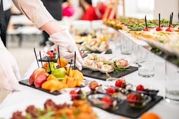 woman hands of a waiter prepare food for a buffet table in a restaurant