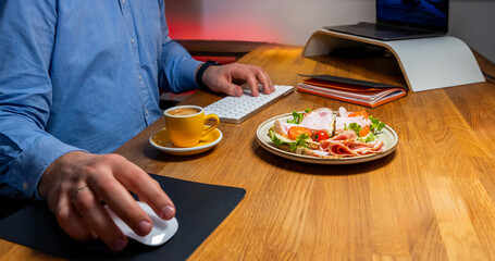 Obraz na płótnie Canvas Businessman enjoying a healthy meal and coffee while working at a modern workspace