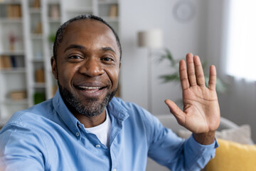 Front person view of african american man in shirt waving hello while starting video call in...