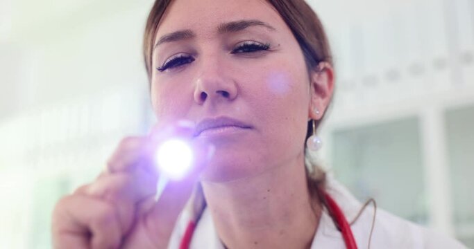 Otolaryngologist or anesthesiologist shines ight into camera