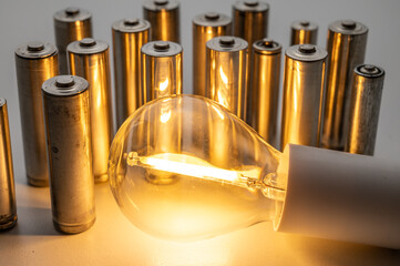Light bulb turned on, with batteries next to it. Accumulation and reuse of renewable energy.
