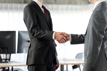 オフィスで握手をするアジア人ビジネスマン	