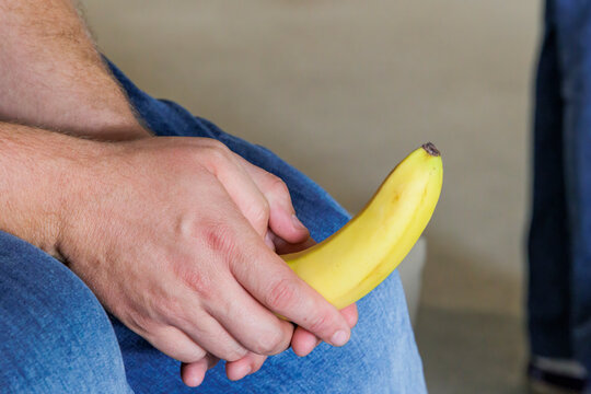 caucasian  Man hand holds a yellow unpeeled banana 