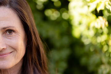 Half portrait of smiling caucasian senior woman in sunny nature with copy space