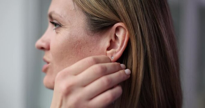 Cute young woman puts on long earrings