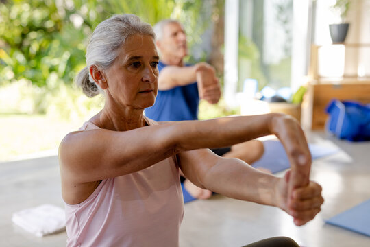 Focused caucasian seniors exercising in pilates class