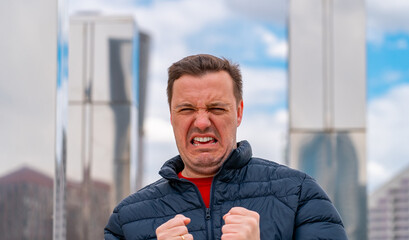 Wintry Discontent: visibly shivering man clenches his fists and grimaces as chilling wind sweeps...