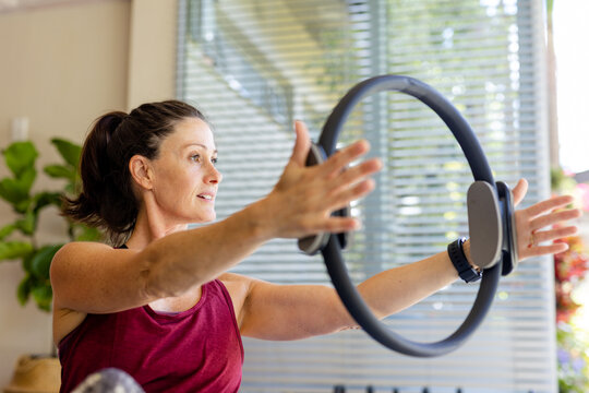 Focused caucasian female coach using exercise ring in pilates class
