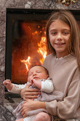 Cherished Moments: A Young Girl Holding Her Newborn Sibling by the Hearth