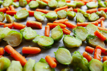 Baby carrots and sliced brussels sprouts on a baking sheet