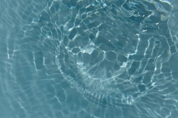 Water surface. Bluewater waves on the surface ripples blurred. Defocus blurred transparent blue colored clear calm water surface texture with splash and bubbles. Water waves with shining pattern.
