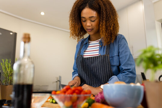 Happy biracial woman preparing food in kitchen chopping vegetables