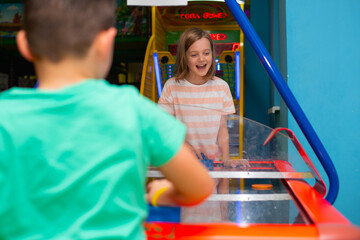 Boy and girl friends play air hockey together in a children's entertainment center	 - 725397822