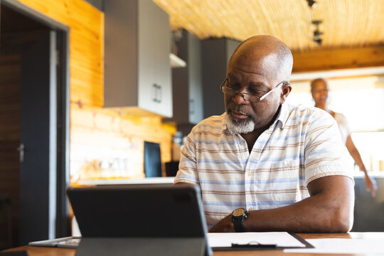 Senior african american man doing paperwork using tablet at home