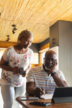 Senior african american couple doing paperwork using tablet at home