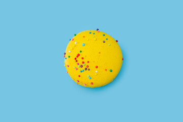Yellow macaroon on blue background. Tasty colorful macaron. Cookie made of two smooth halves, with...