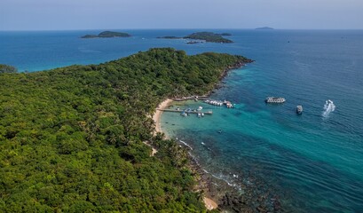 Fototapeta na wymiar Aerial view of a tropical island with lush greenery, a sandy beach, and boats on clear blue waters, ideal for vacation and travel concepts, Earth Day concept