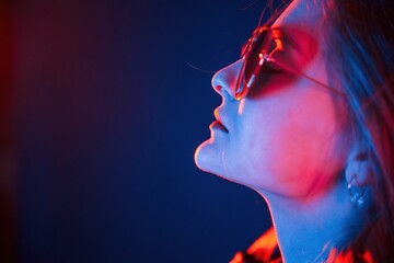 Side view, in eyewear. Cool young woman portrait in neon colors - Powered by Adobe