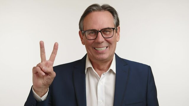 Relaxed and friendly businessman in a blue suit making a peace sign, conveying a message of positivity and approachability. High quality 4k footage