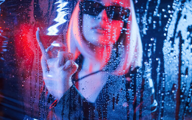 In black sunglasses. Stylish woman with white hair is behind wet transparent plastic sheet