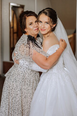 A beautiful and happy mother and her daughter, the bride, are standing next to each other. The best day for parents. Tender moments at the wedding.