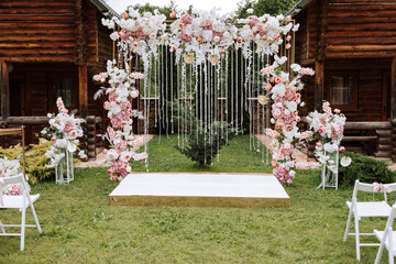 golden arch decorated with flowers on the background of trees. A white path that leads to the arch,...