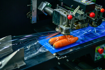 Carrots are being wrapped in plastic on a production line. Carrot packaging for sale
