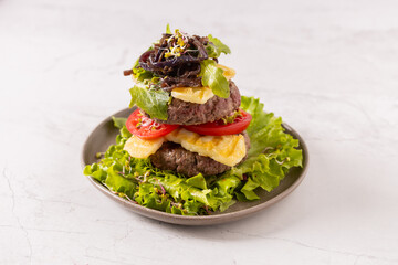 Beef burger without a bun, served on a plate with halloumi cheese.