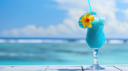 Blue hawaii cocktail on white wooden table with blue sea and sky background.