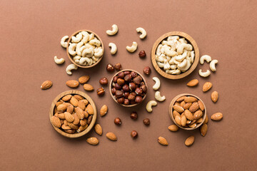 Assortment of nuts in wooden bowl on colored table. Cashew, hazelnuts, walnuts, almonds. Mix of nuts Top view with copy space