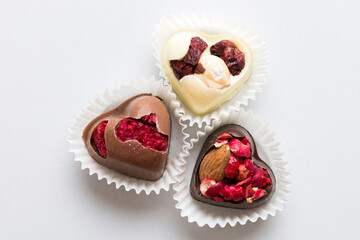 chocolate sweets in the form of a heart with fruits and nuts on a colored background. top view with space for text, holiday concept