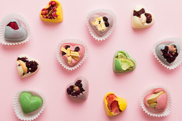 chocolate sweets in the form of a heart with fruits and nuts on a colored background. top view with space for text, holiday concept