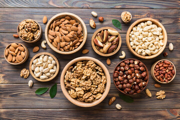 mixed nuts in wooden bowl. Mix of various nuts on colored background. pistachios, cashews, walnuts, hazelnuts, peanuts and brazil nuts