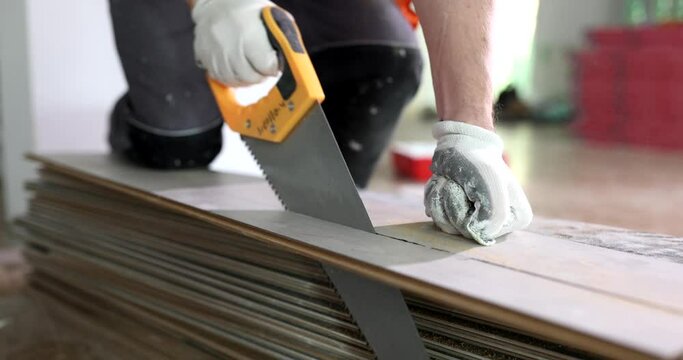 Working master cutting piece of laminate using hand saw. Measurement and cutting flooring