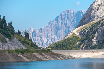 The mountain named "Civetta", in the Dolomiti mountain chain, Italy. Waters of the lake named "Fedaia" in the foreground. Blue sky on the background.