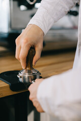Close-up, the barista works with a temperer. The process of making coffee.