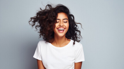 Young happy smiling Indian woman model wearing tshirt looking at camera standing on color background. Face skin care cosmetics makeup, fashion ads. Beauty portrait. White t-shirt mock up template . - obrazy, fototapety, plakaty