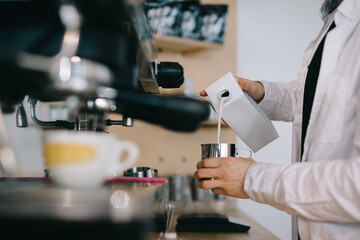 Barista prepares milk for cappuccino. Close-up of a man preparing coffee in a cafe.
