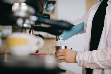 Barista prepares milk for cappuccino. Close-up of a man preparing coffee in a cafe.