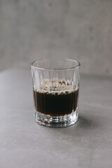 Freshly brewed drip coffee in a glass mug. A cup of coffee on a gray background.