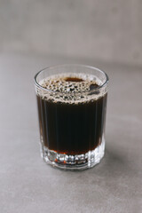 Freshly brewed drip coffee in a glass mug. A cup of coffee on a gray background.