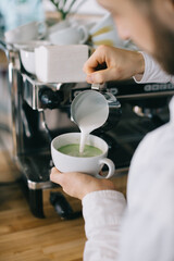 Fototapeta na wymiar Barista prepares tasty and healthy matcha latte tea..