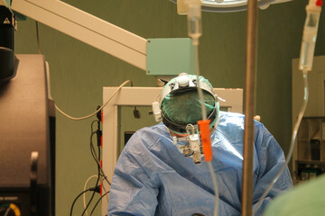 Doctors are surgery to patient at operating room. the doctor's head with special glasses for...