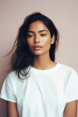 Fototapeta premium Young pretty cool Indian woman model wearing tshirt looking at camera standing on color background. Face skin care cosmetics makeup, fashion ads. Beauty portrait. White t-shirt mock up template .
