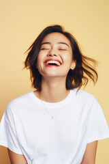 Fototapeta premium Young happy smiling Asian woman model wearing tshirt looking at camera on color background. Face skin hair care korean cosmetic and makeup, fashion ads. Beauty portrait. White t-shirt mock up template