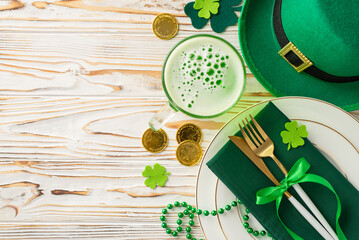 Commemorate St. Paddy's Day at the pub setting. Overhead shot of table set with plate, utensils,...