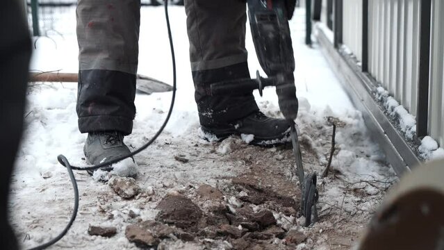 Builder Drills a hole in the wall with a Hammer Drill. Close-up of hammer drill perforator making hole	