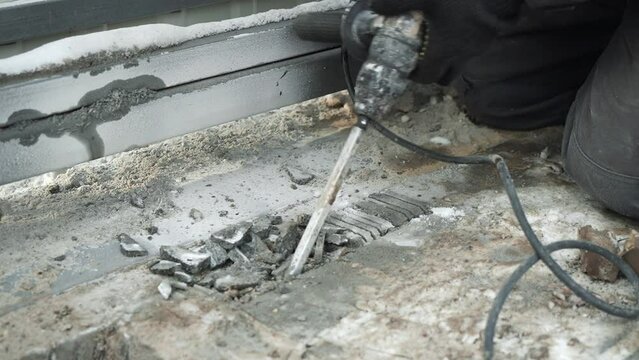 Builder Drills a hole in the wall with a Hammer Drill. Close-up of hammer drill perforator making hole	